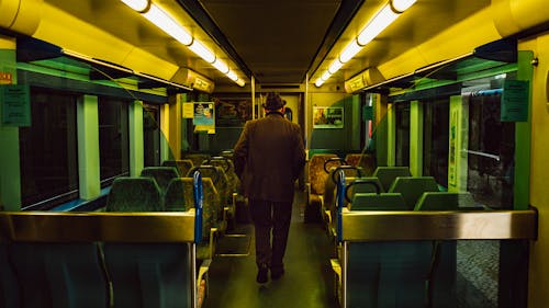 Man in Brown Coat Walking Inside the Train 