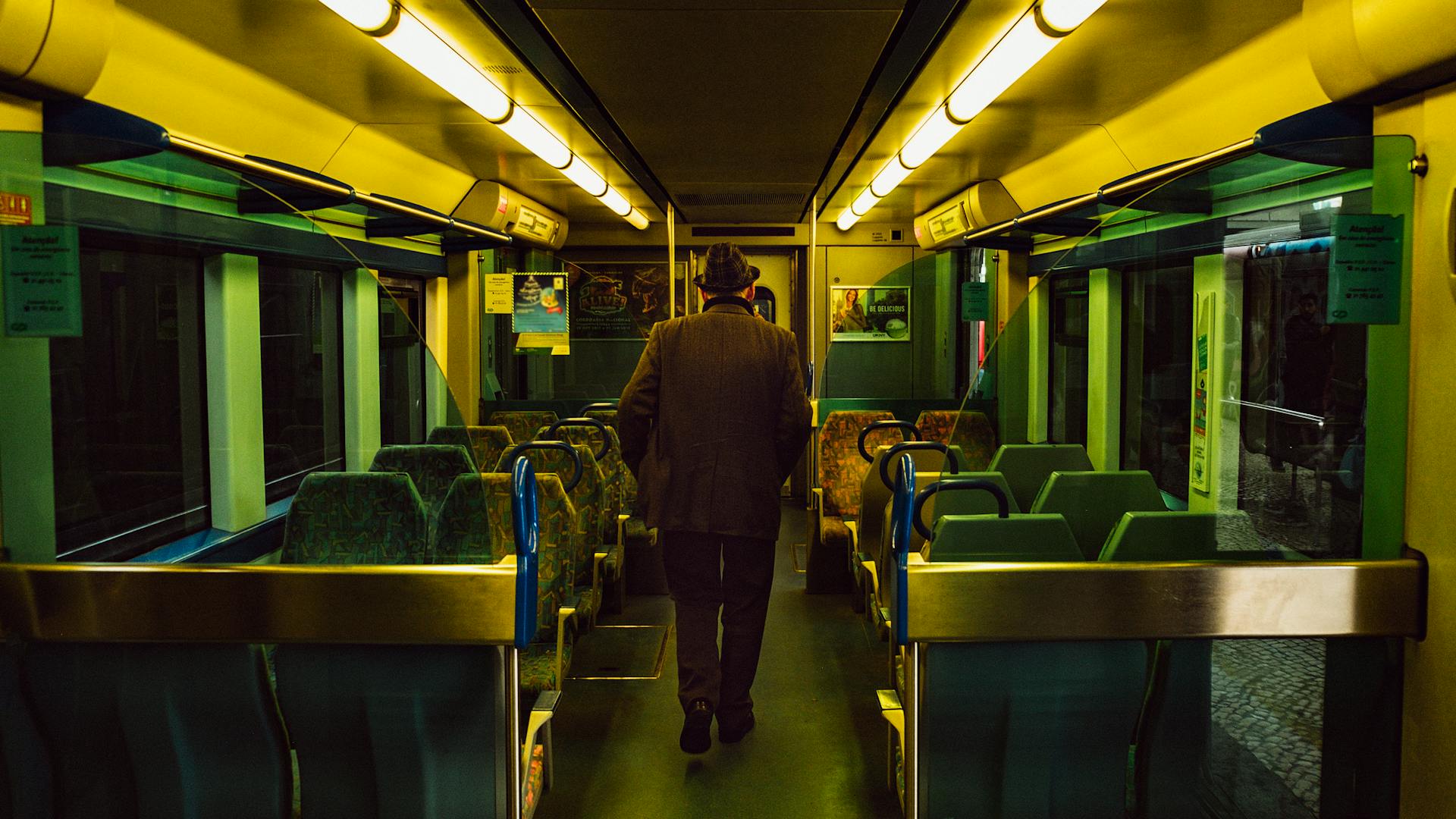 A man walking through a train aisle in Lisbon's public transportation system.