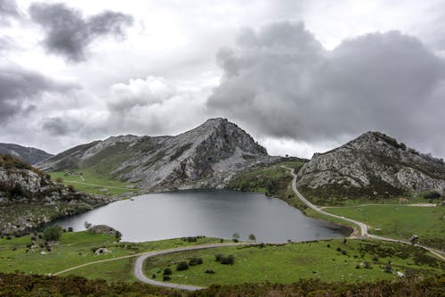 Photo of Lake and Rocky Mountain Under Cloudy Sky