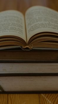 A detailed close-up photo of an open book placed on a stack, highlighting vintage pages.