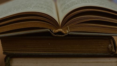 Free Macro shot of an open vintage book on top of a stack, showcasing its old pages. Stock Photo