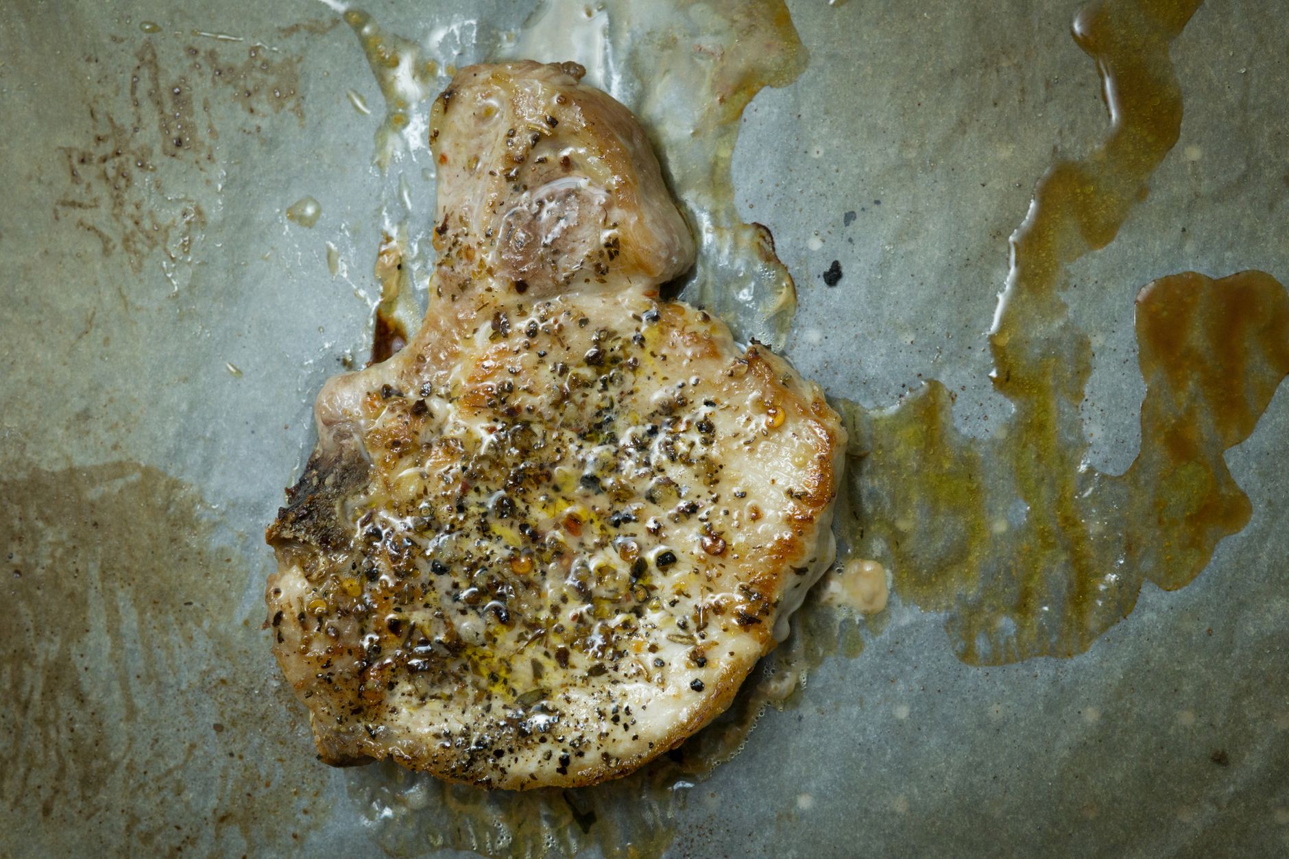 Grilled pork chops on a cast iron skillet with herbs and lemon slices