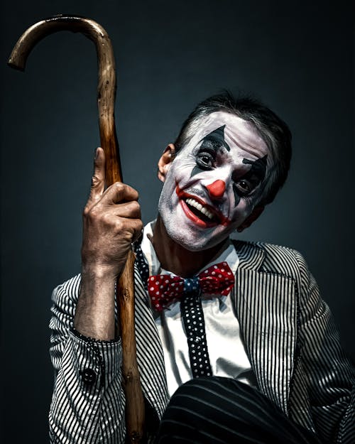 Man in Clown Make-up holding a Brown Wooden Cane 
