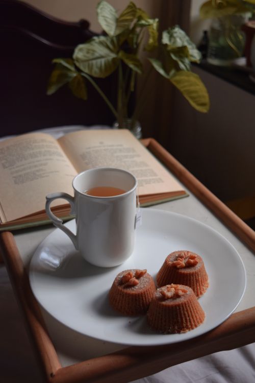 Free From above arrangement of cup of aromatic tea placed on plate with delicious chocolate cupcakes served on bed tray near opened book Stock Photo