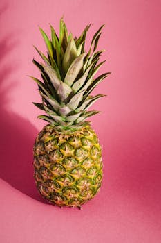 Close-up of a ripe pineapple against a colorful pink studio backdrop.