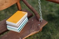 Stack of books placed on seat of wooden swing