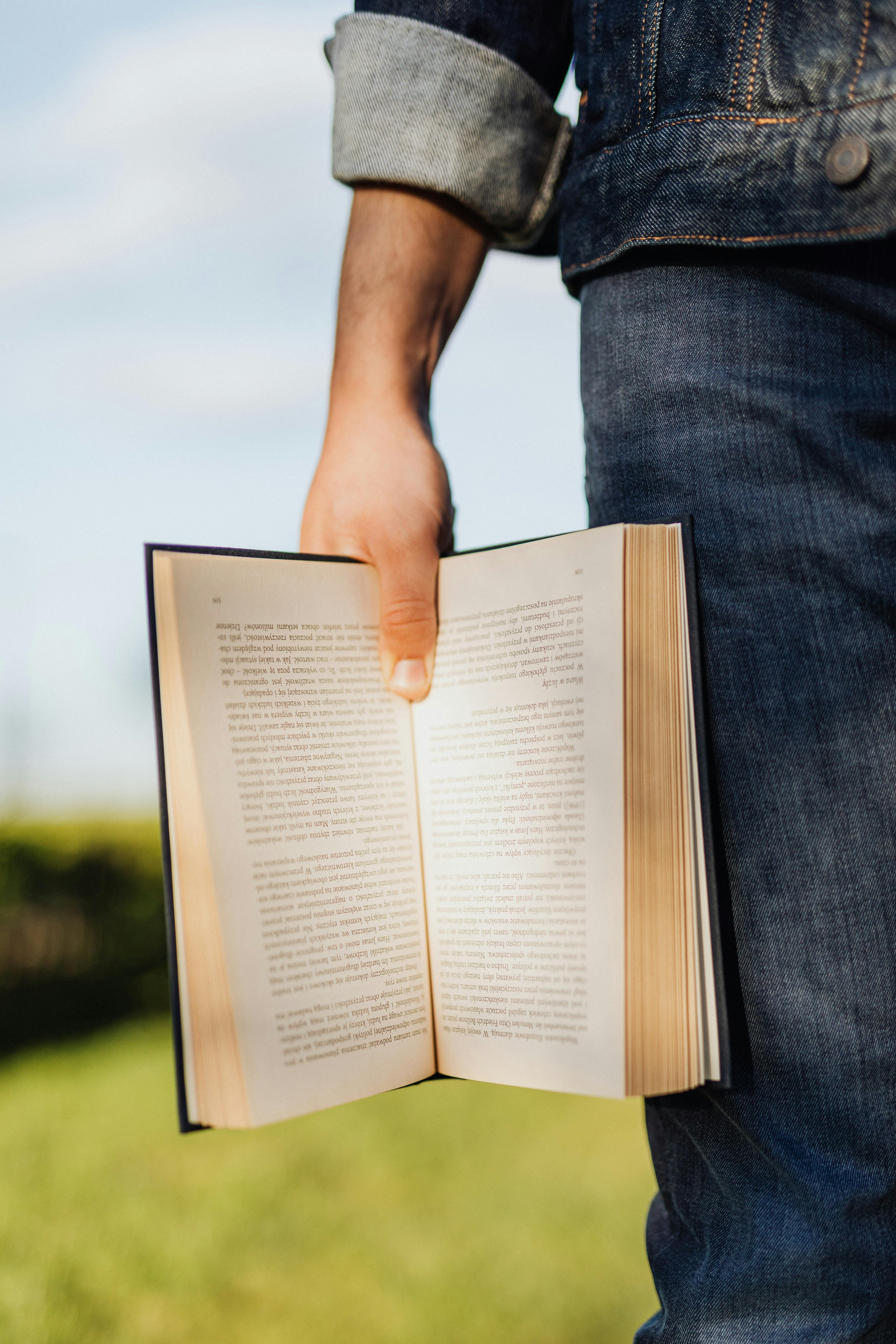 crop male student with open book lit up by sunlight