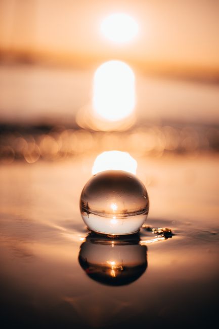 Scenery of small transparent glass ball on still lake water surface under evening sun lighting