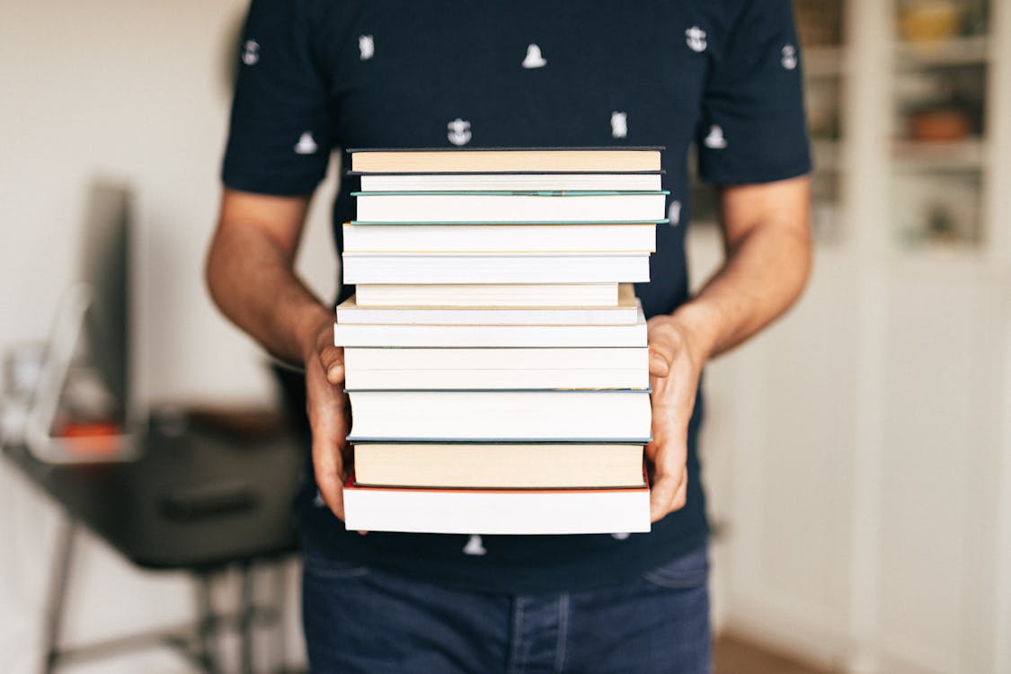Free Person Carrying a Stack of Books Stock Photo
