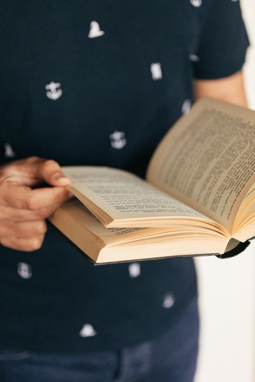 Free Hands holding an open book, focusing on the pages and text, creating a reading ambiance. Stock Photo
