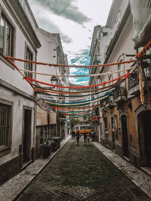 Free Narrow paved pedestrian street between old low level apartment buildings decorated with hanging tinsels Stock Photo