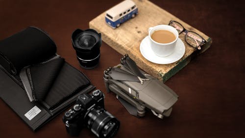 Modern photo camera drone and cup of coffee on table