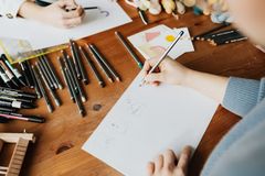 Designers sketching wordmark concepts with pencils at a wooden desk — photo by Kaboompics on Pexels
