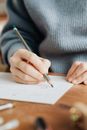 Crop unrecognizable female designer drawing on paper in office