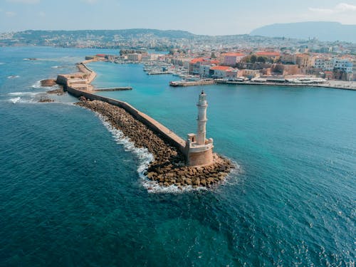 White Lighthouse on Island Surrounded by Body of Water