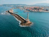 无人机在风景优美的沿海背景下，捕捉到历史悠久的威尼斯港口哈尼亚，并展示了其标志性灯塔