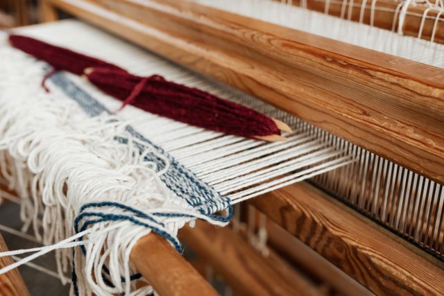 Warp threads and a shuttle on a wooden table loom, photo by Kaboompics on Pexels