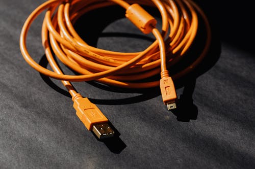 Free From above of orange usb to micro usb cable twisted into ring placed on black board Stock Photo