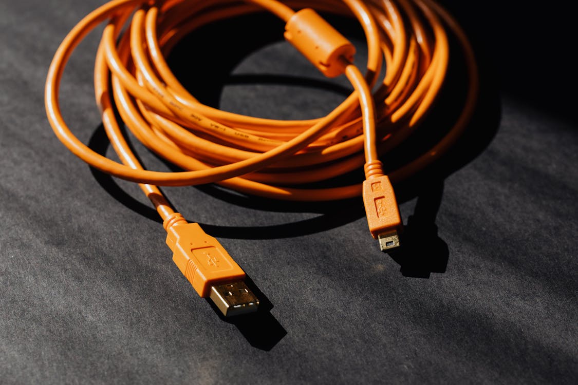 Free From above of orange usb to micro usb cable twisted into ring placed on black board Stock Photo