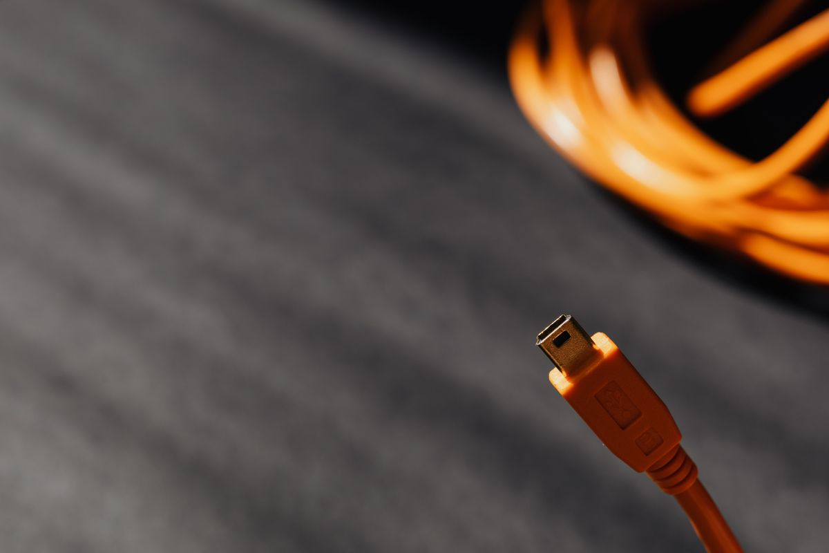 Close-up van een oranje USB-kabelstekker op een donkere stof