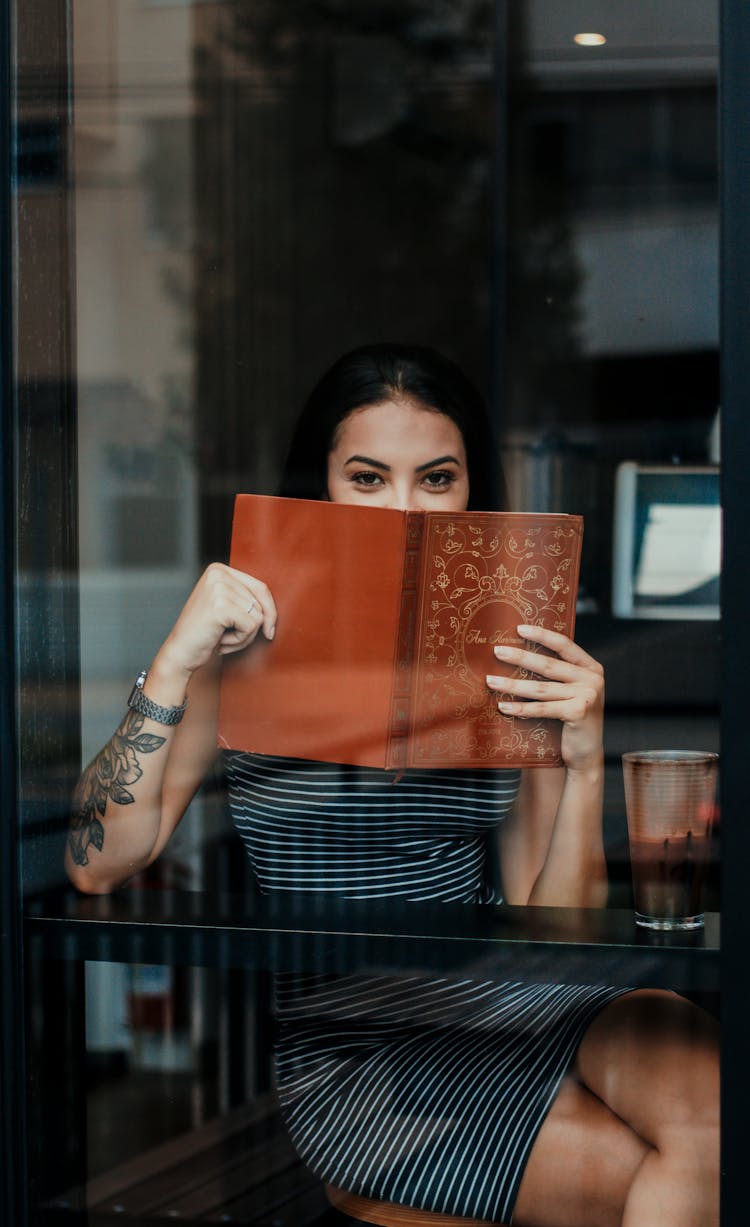 Cheerful Woman Covering Mouth With Menu While Relaxing In Cafeteria