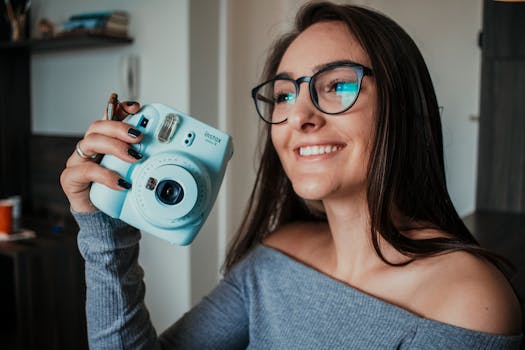 A happy woman holding an instant camera indoors, exuding joy and style.