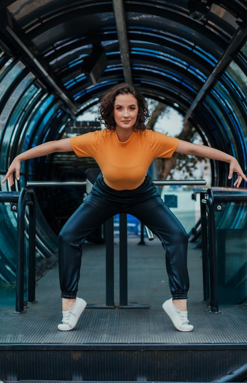 Cheerful young woman doing dance movements on street