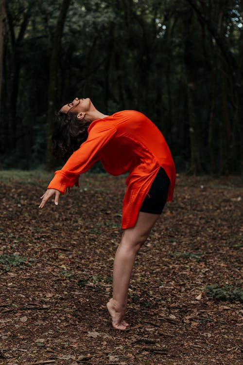 Photo of Woman Wearing Orange Long Sleeves While Bending Her Body