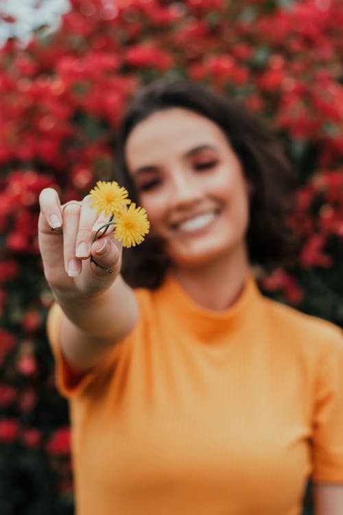 Shallow Focus Photo of Woman Holding Yellow Flowers