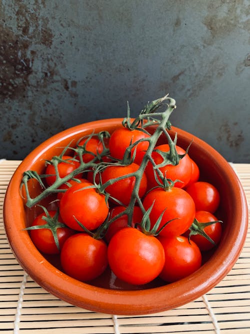 From above bunch of fresh ripe red tomatoes placed in ceramic bowl in kitchen