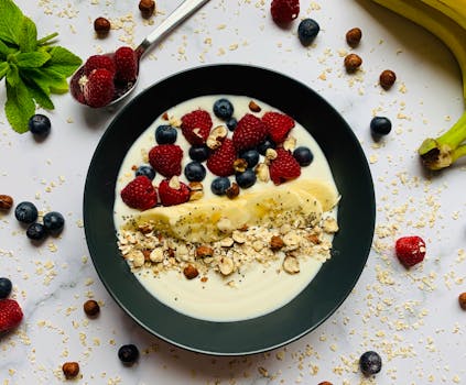 Delicious fruit and yogurt bowl with berries, banana, and nuts for a nutritious breakfast.