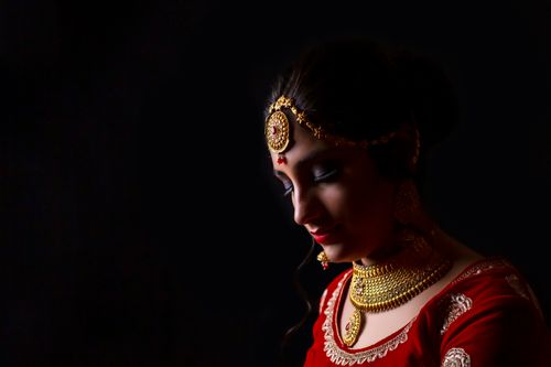 Free Portrait of an Indian woman adorned with golden jewelry on a dark background. Stock Photo