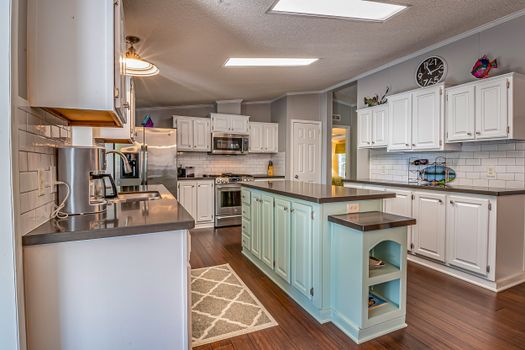 A spacious kitchen featuring white cabinets, modern appliances, and a central island with seating.