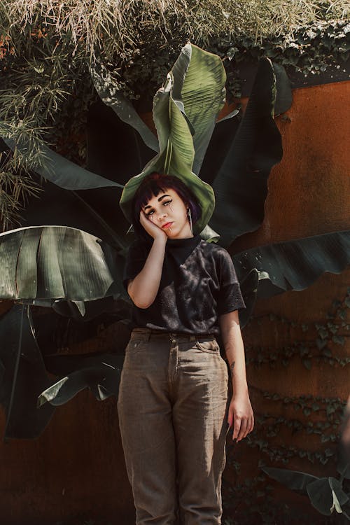 Young Woman Standing in Front of Giant Plant 