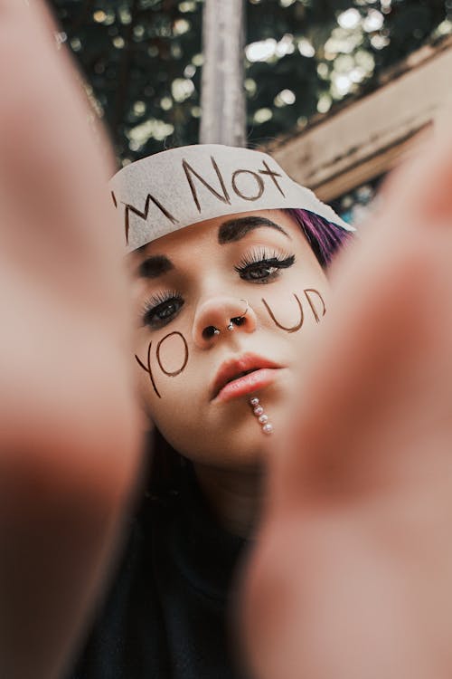 Girl with Face Piercing and a Message Written on Her Cheeks and Forehead