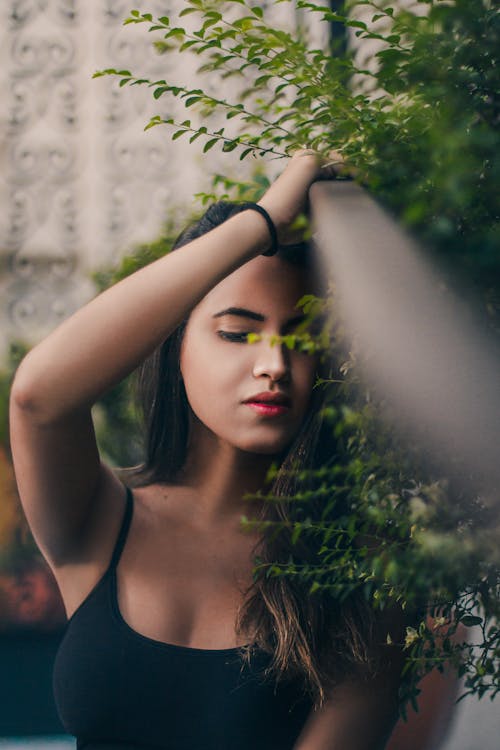 Woman Standing Next to a Plant with an Arm Raised