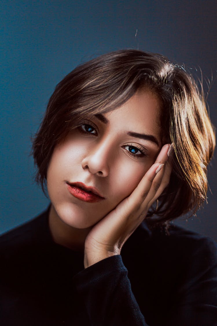 Tired Young Woman Leaning Cheek On Hand And Looking At Camera