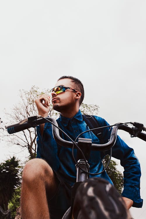 Trendy young cyclist resting on bike in countryside