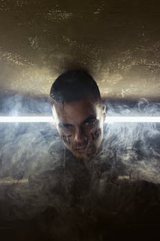 这幅引人入胜的肖像画描绘了一名男子，他在烟雾与昏暗的灯光中面部带有铭文，唤起了神秘感