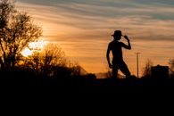 Silhouette of Man Standing on Grass Field during Sunset