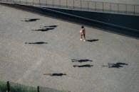 Girl in Pink Shirt and Black Pants Walking on Gray Concrete Pathway