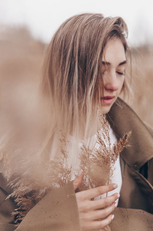 Close-Up Shot of a Woman Holding Brown Grass