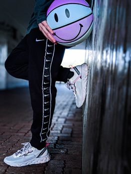 A close-up of sneakers and a basketball with a smiley face, showcasing street style.