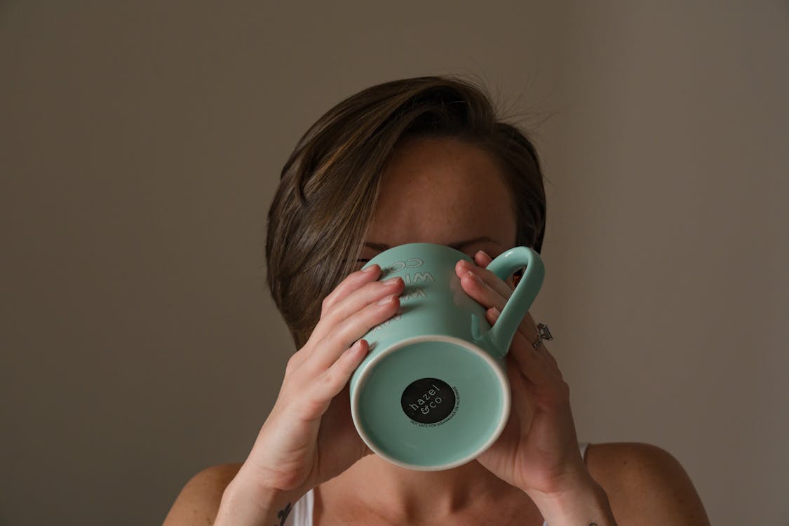 Photo of Woman Drinking from a Teal Mug