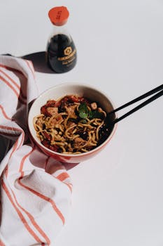 A mouthwatering Asian noodle dish with chopsticks, ideal for food bloggers and culinary enthusiasts.