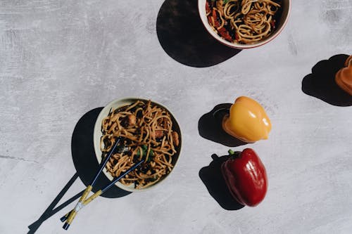 Bowls of Noodles with Chopsticks and Bell Peppers