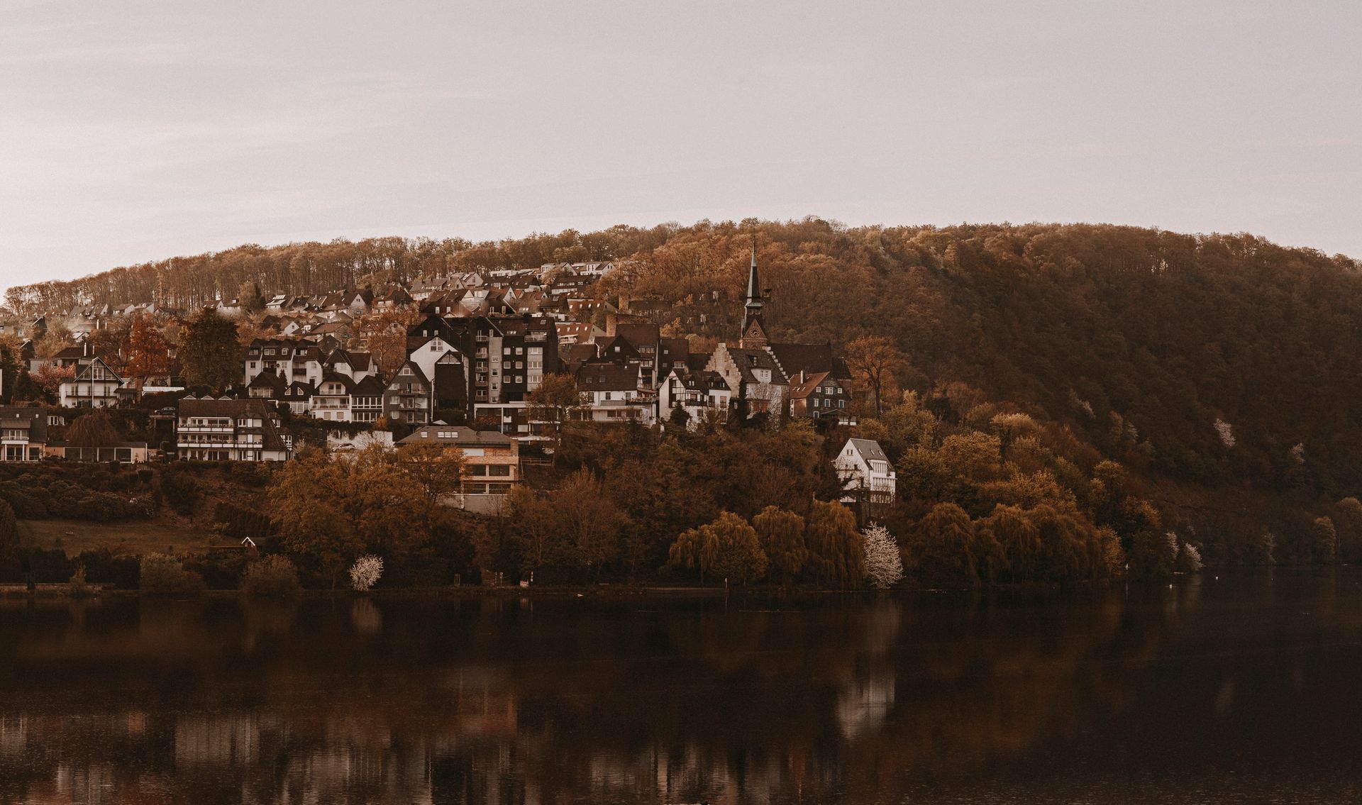 Charming hillside town in Hagen, Germany with autumn colors and reflection in the river.
