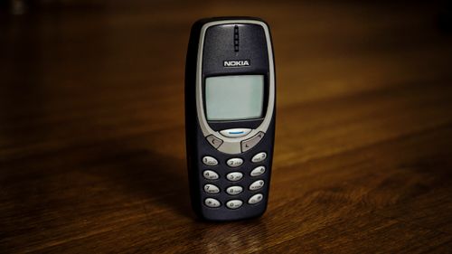 Free Small old mobile phone with monochrome screen and buttons placed on wooden table Stock Photo