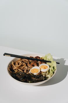 A flavorful ramen bowl featuring noodles, boiled egg, and fresh greens, captured in natural light.