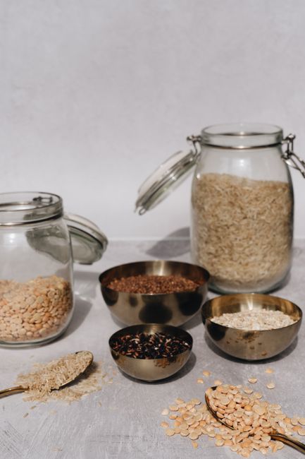 Incorporate dry fruits into daily diet - Buying Tips for Choosing Quality Dry Fruits | A variety of grains and cereals in glass jars and metal bowls on a table.